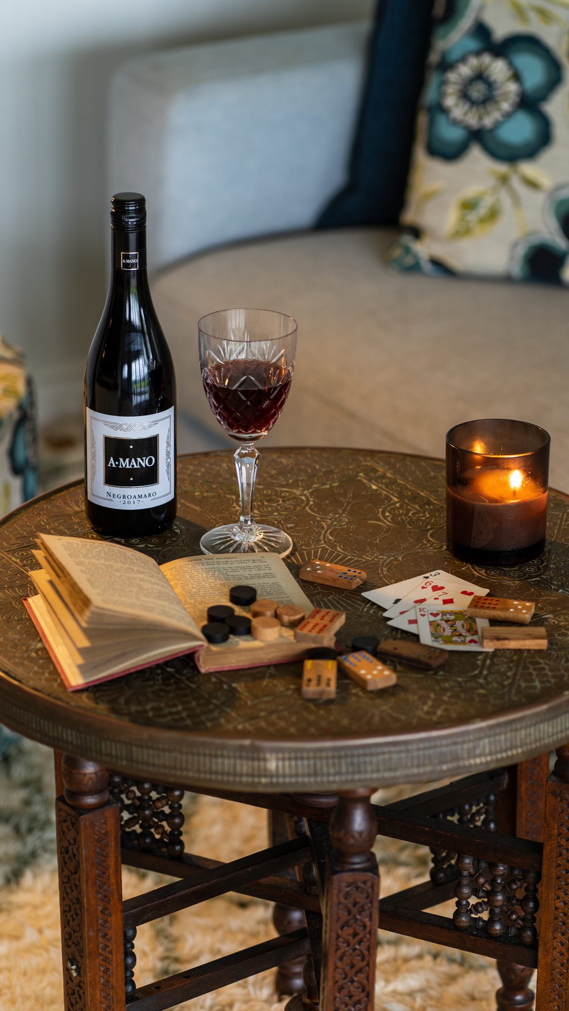red wine games book playing cards and a lit candle in the sitting room of heartwood farm cottage