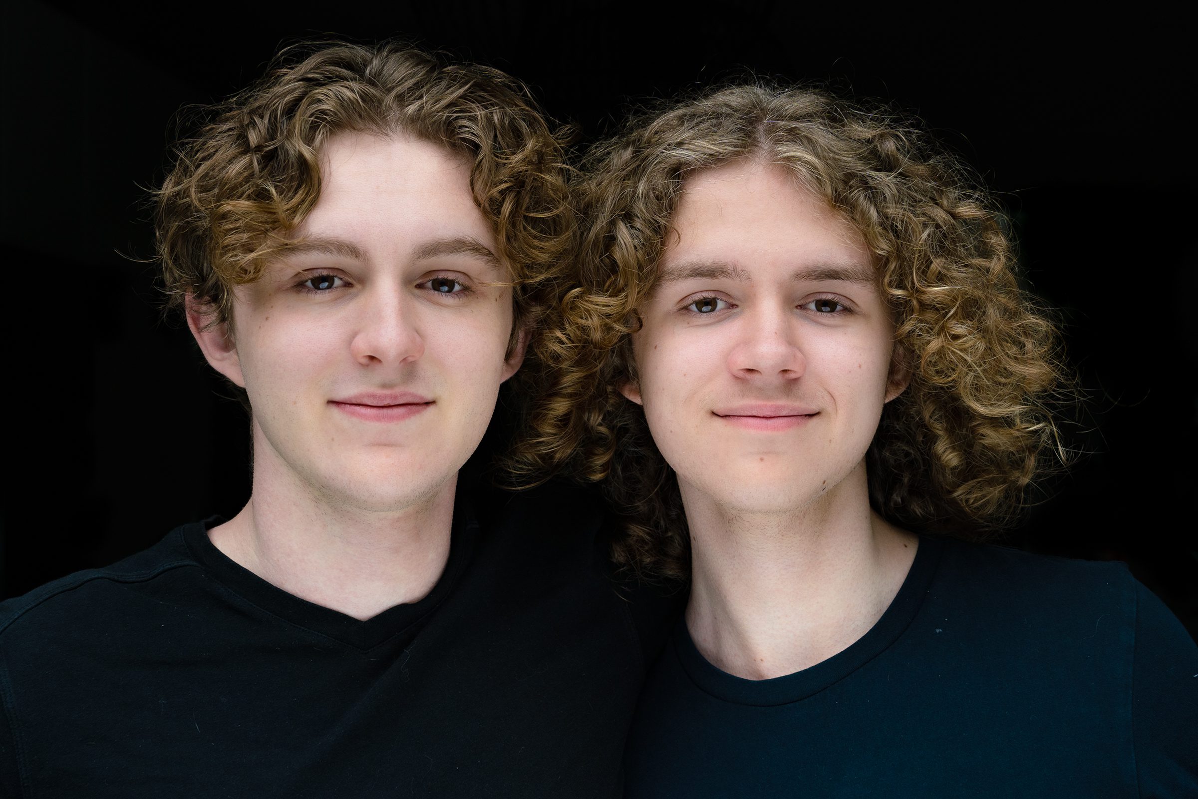 portraits of young teenage brothers with blonde curly hair looking directly at the camera standing side by side