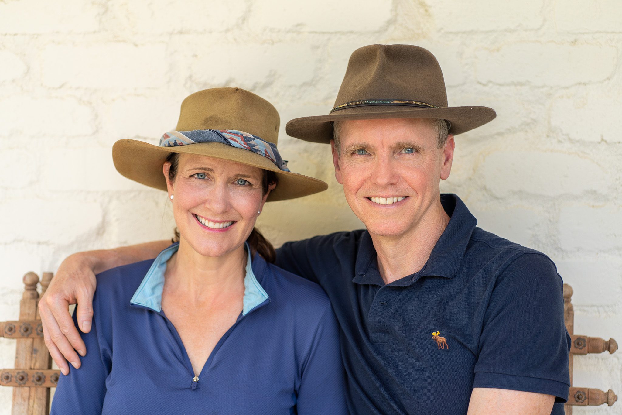 couple wearing Australian country hat sitting on a bench while they are photographed for the portraits page