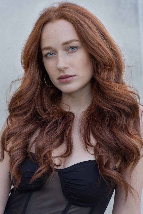 Headshot of a model with long red hair and blue eyes looking directly at the camera and being photographed by Georgie Greene Photography for the prices web page