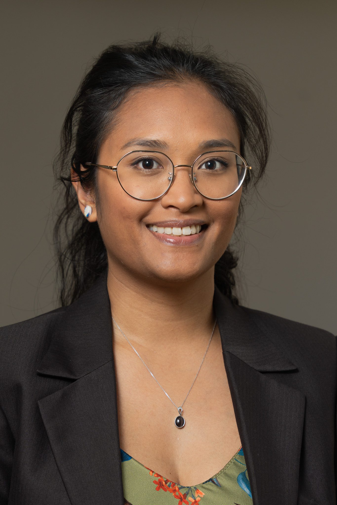 young asian woman with her hair tied back wearing glasses and looking into the camera as her corporate headshots are taken