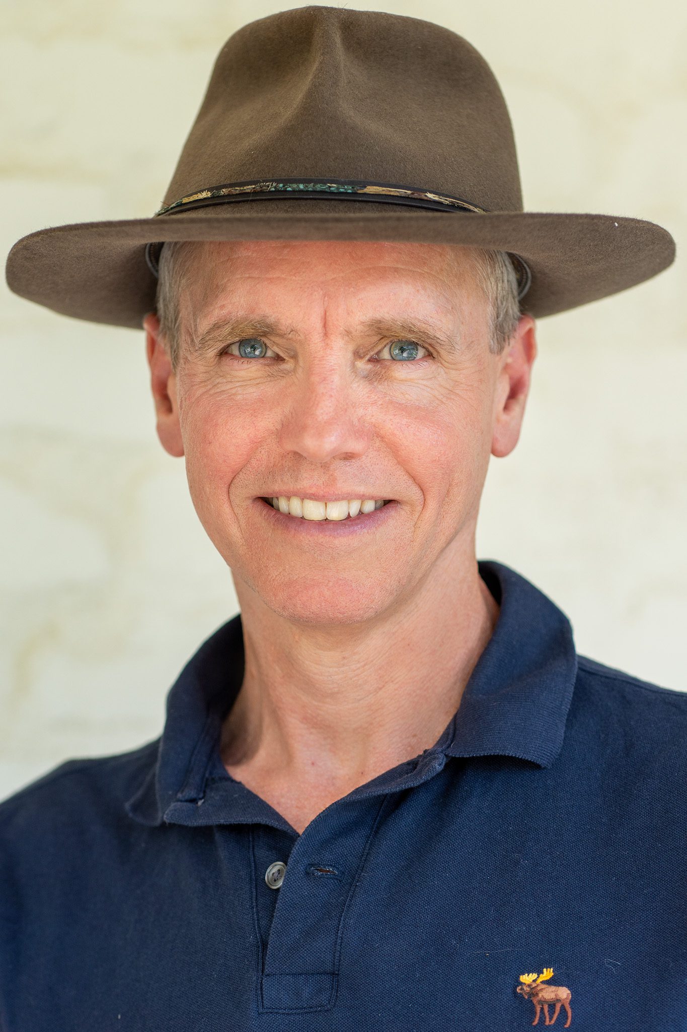 a white middle-aged man with short hair wearing a hat and looking into the camera as his corporate headshots are taken