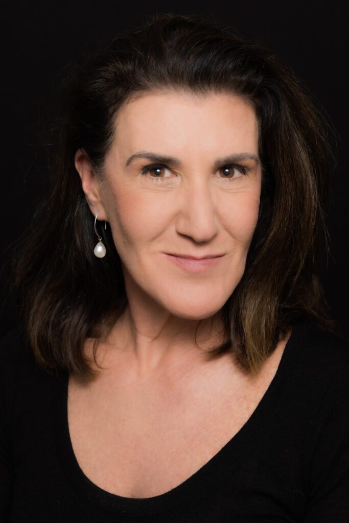 a middle-aged woman with shoulder-length dark hair wearing black and looking into the camera as her corporate headshots are taken