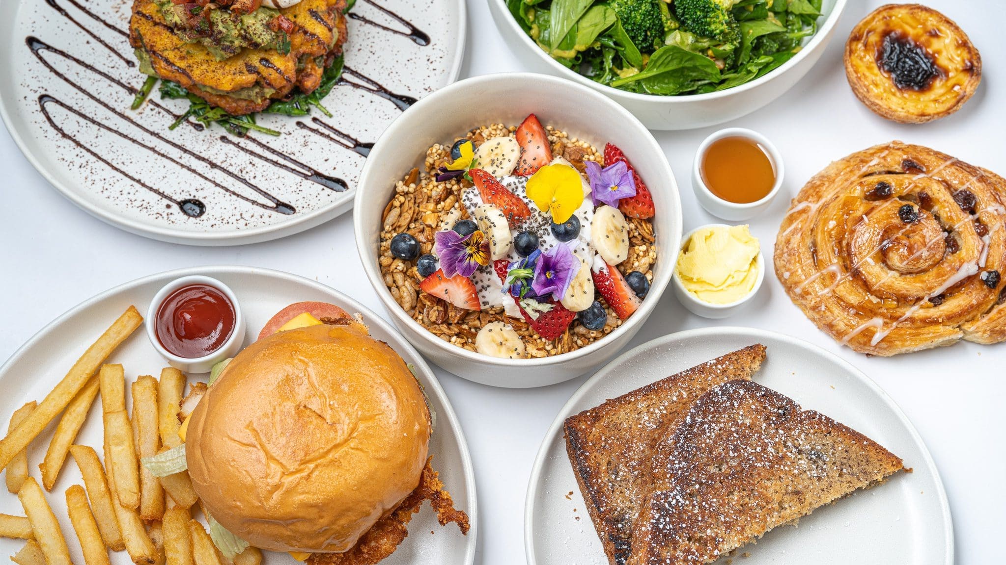 Overhead view of a variety of food including granola toast pastry snail burger and chips photographed by Georgie Greene Photography as a hero shot for a food delivery app