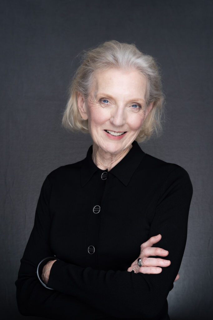 Corporate Headshot of older woman with white hair wearing a black top