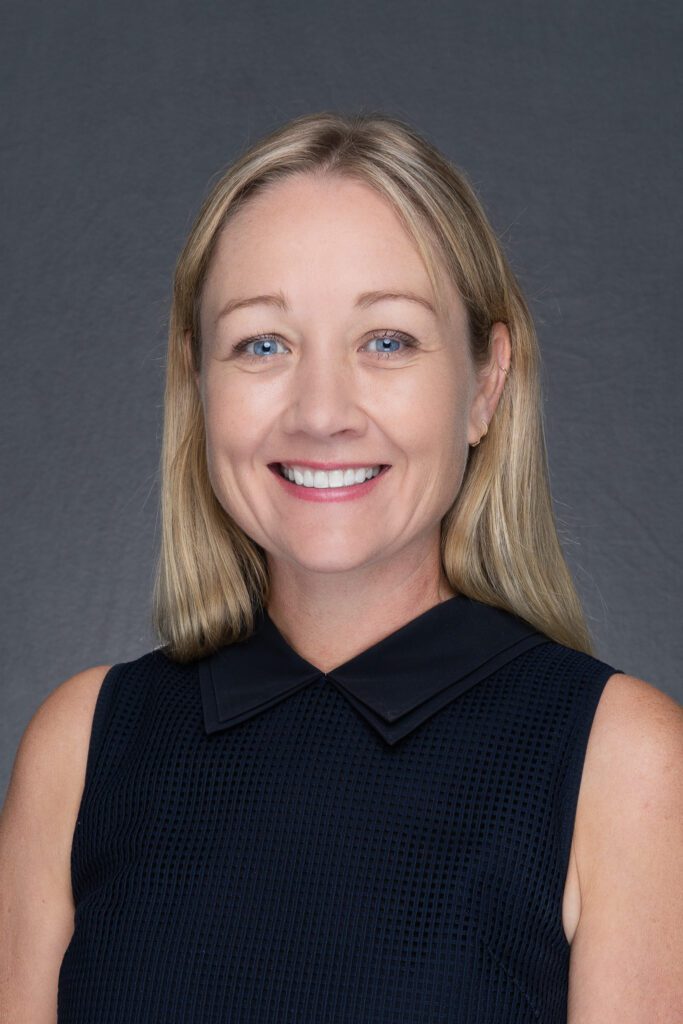a professional woman with long blonde hair and blue eyes wearing a black top and having her corporate headshots taken by Georgie Greene Photography