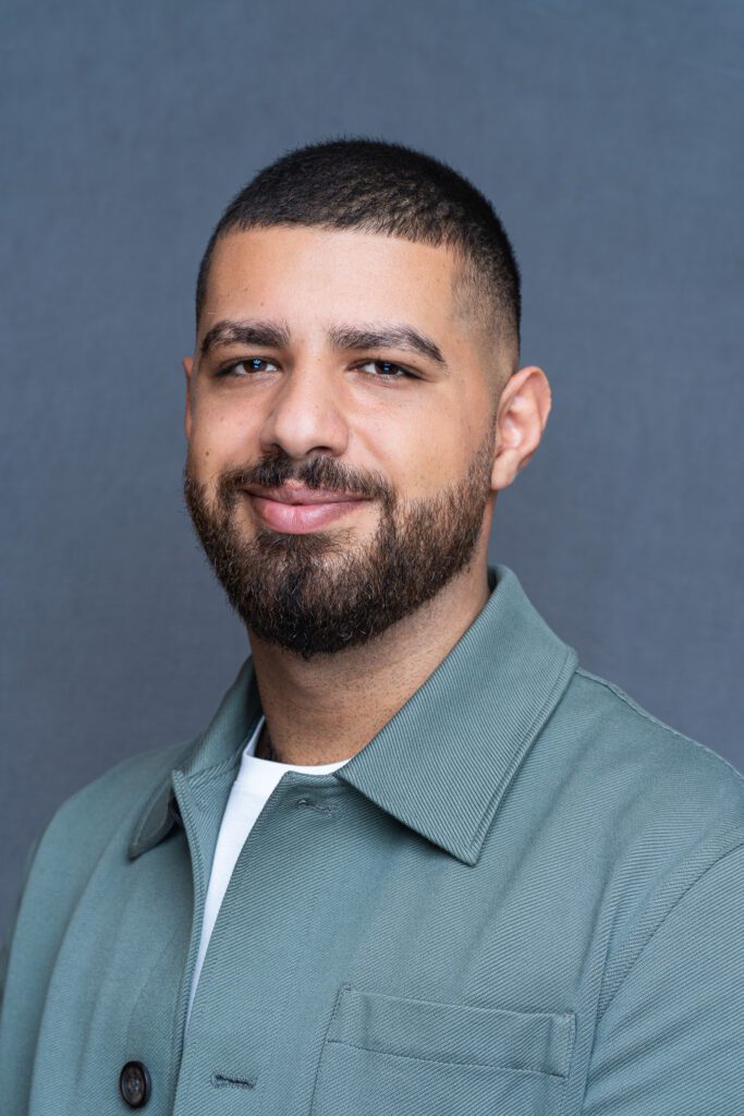 bearded Man with short dark hair wearing a green jacket as he smiles into the camera having his professional headshots taken by Georgie Greene Photography