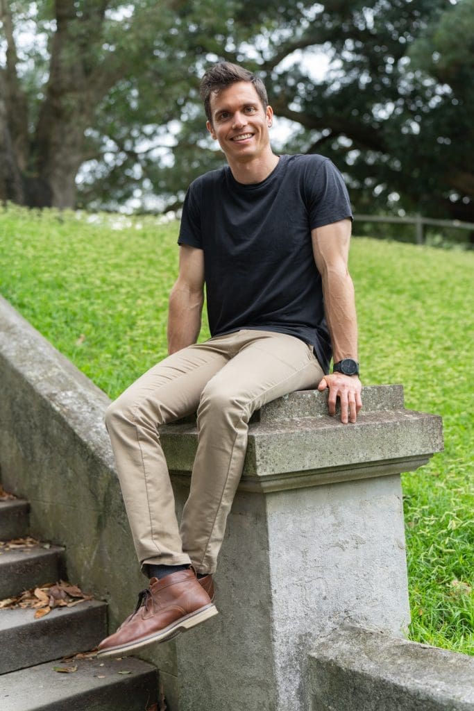 Ext: Young man sitting on a stone post having dating app photography taken by dating photographer Georgie Greene in Sydney NSW