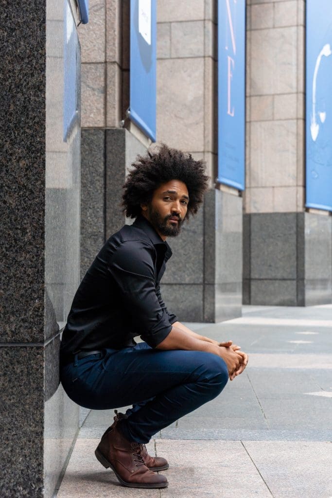 Ext: Young black man in black having his online dating photo taken by dating photographer Georgie Greene in Sydney NSW