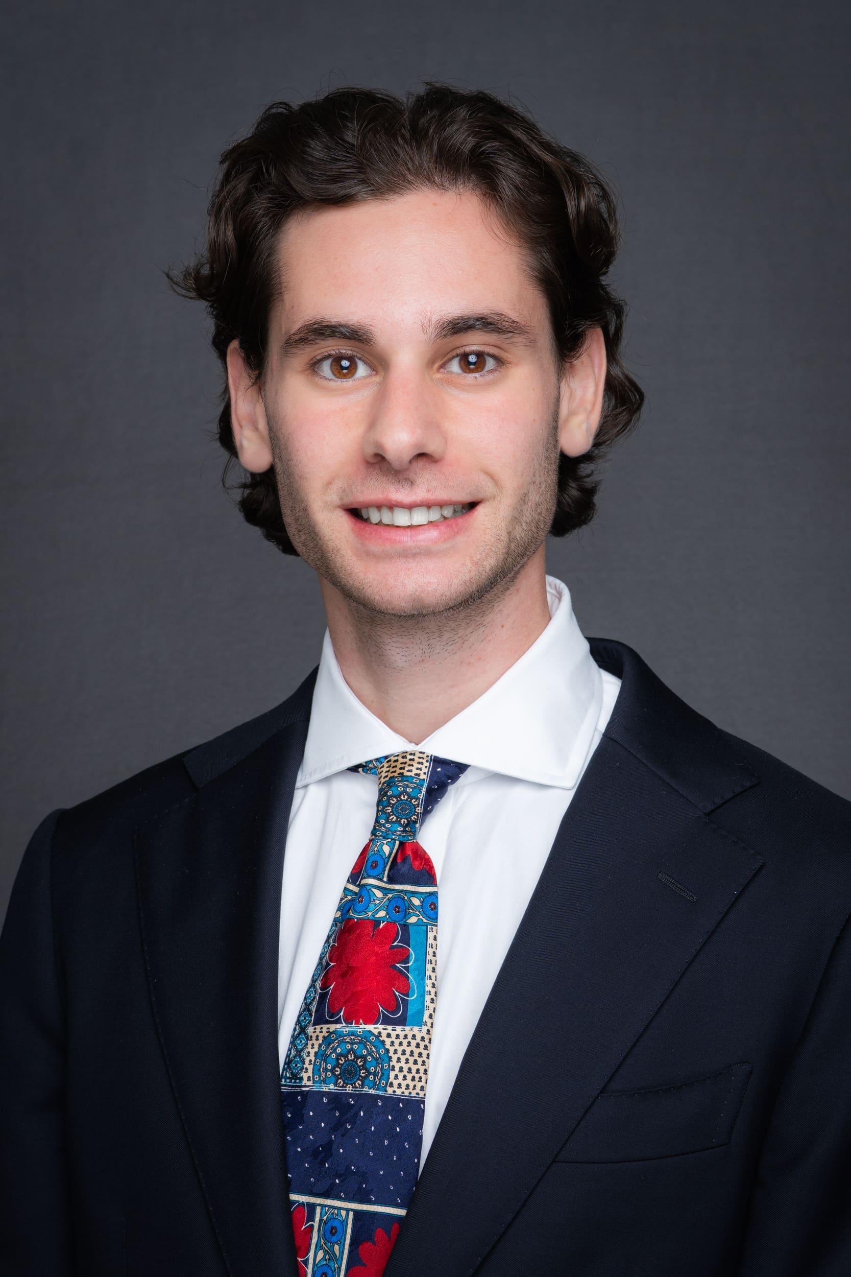 Young dark haired man wearing a colourful tie having his headshot taken with a mobile studio headshot set-up in Sydney NSW