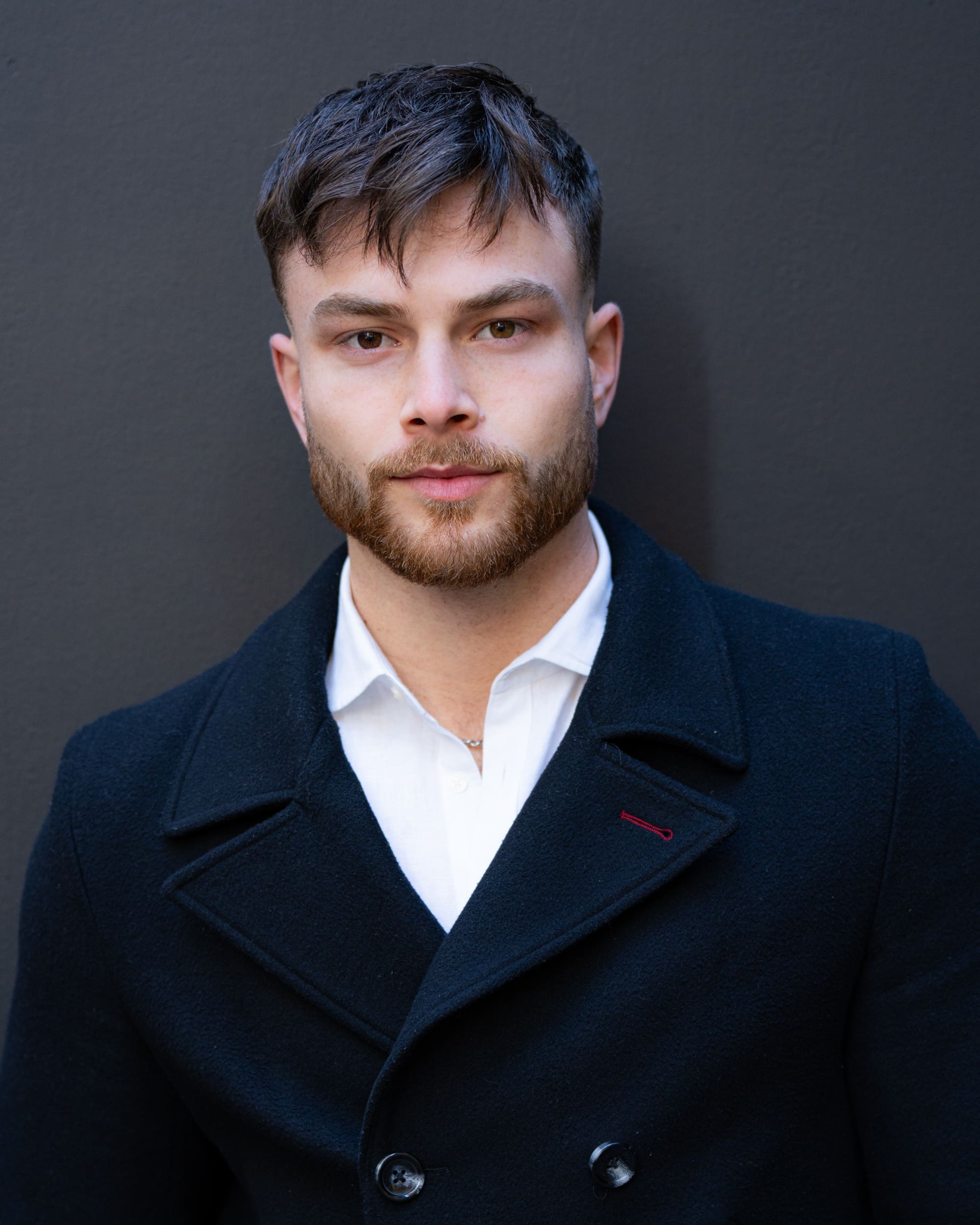 Dark haired bearded young man in blue jacket having his actor headshot taken by headshot photographer Georgie Greene