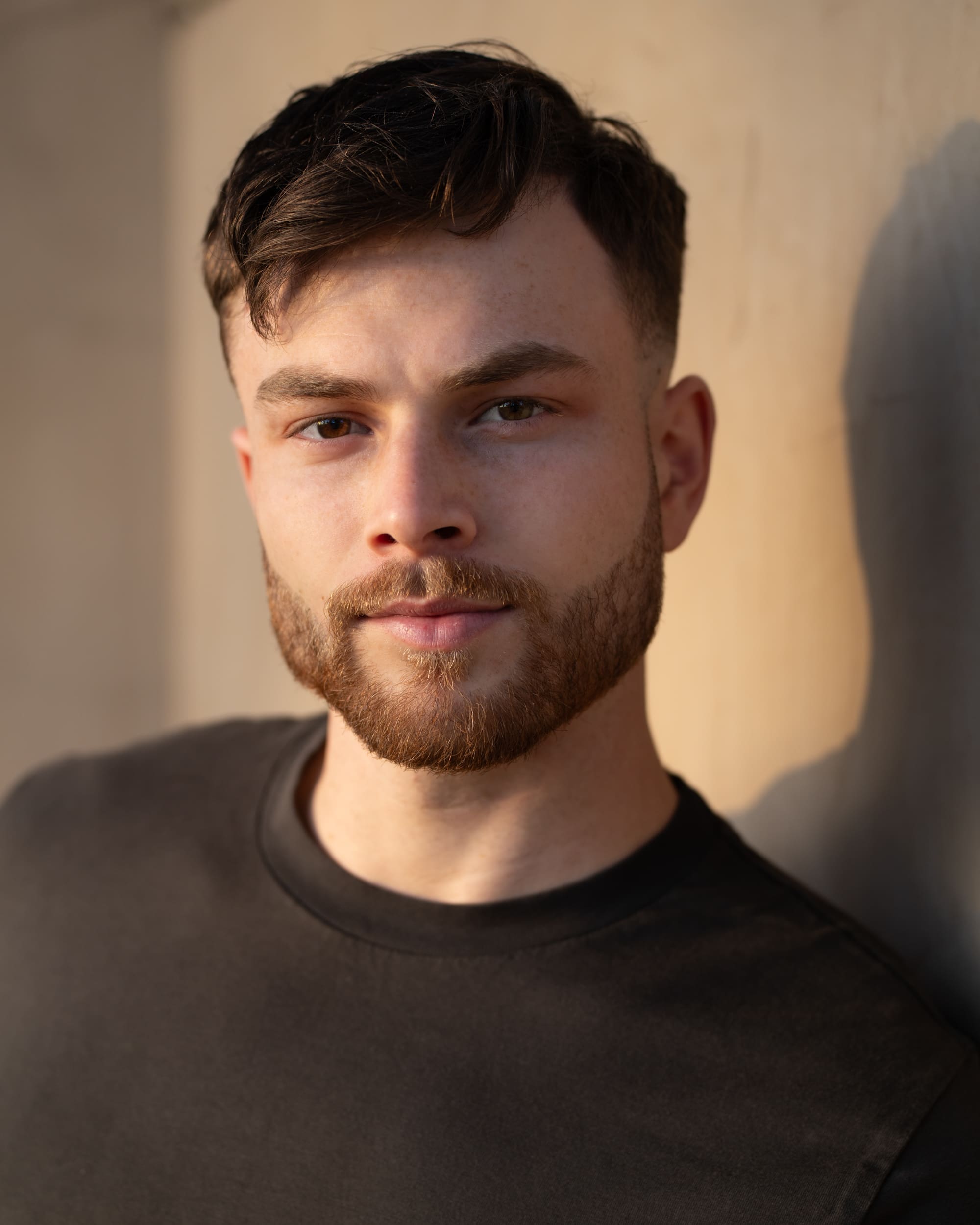 Dark haired bearded young man in dark top having actor headshots taken by Sydney headshot photographer Georgie Greene