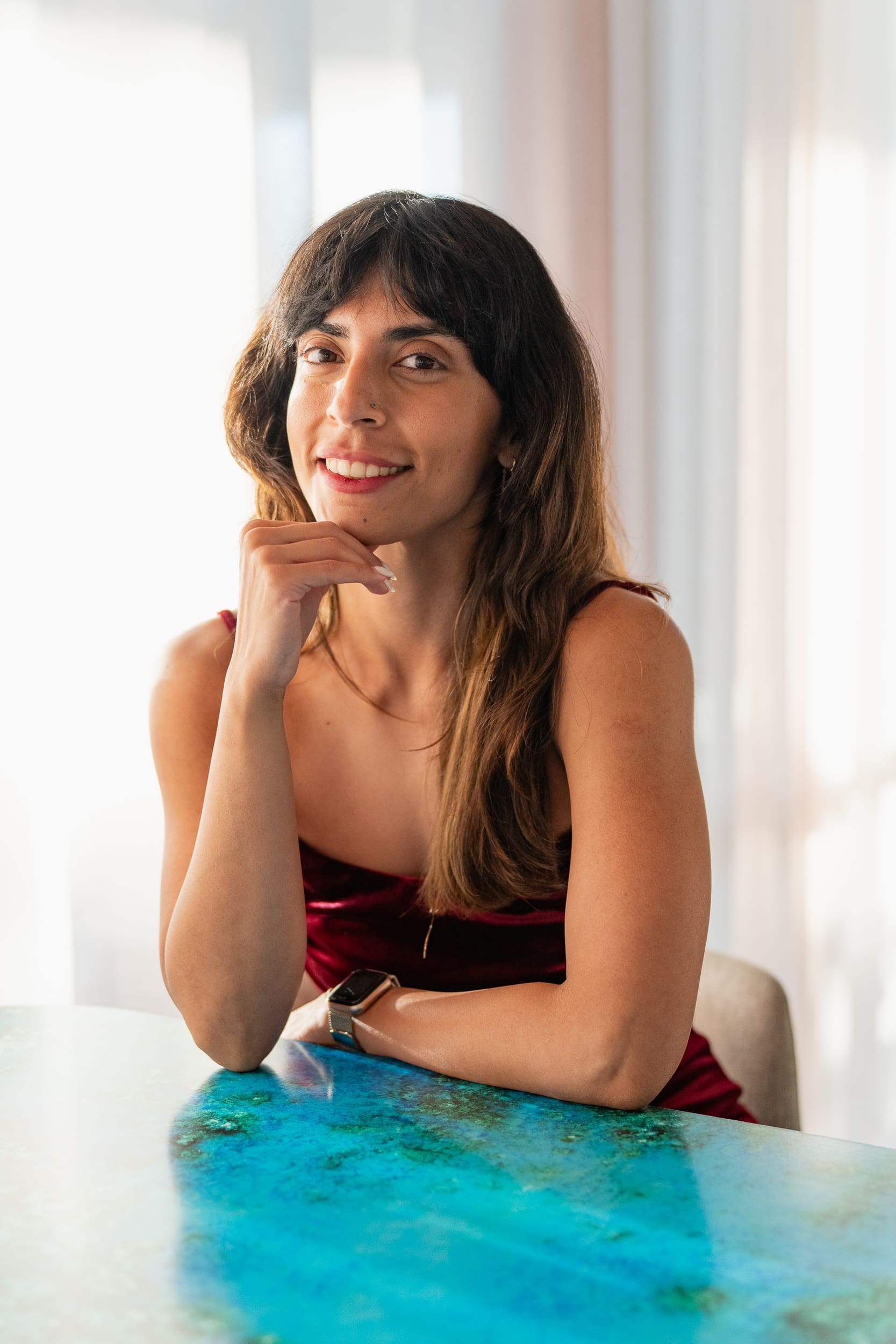 Indian Yoga Teacher wearing red and sitting at a table having her personal branding headshot taken by Sydney headshot photographer Georgie Greene