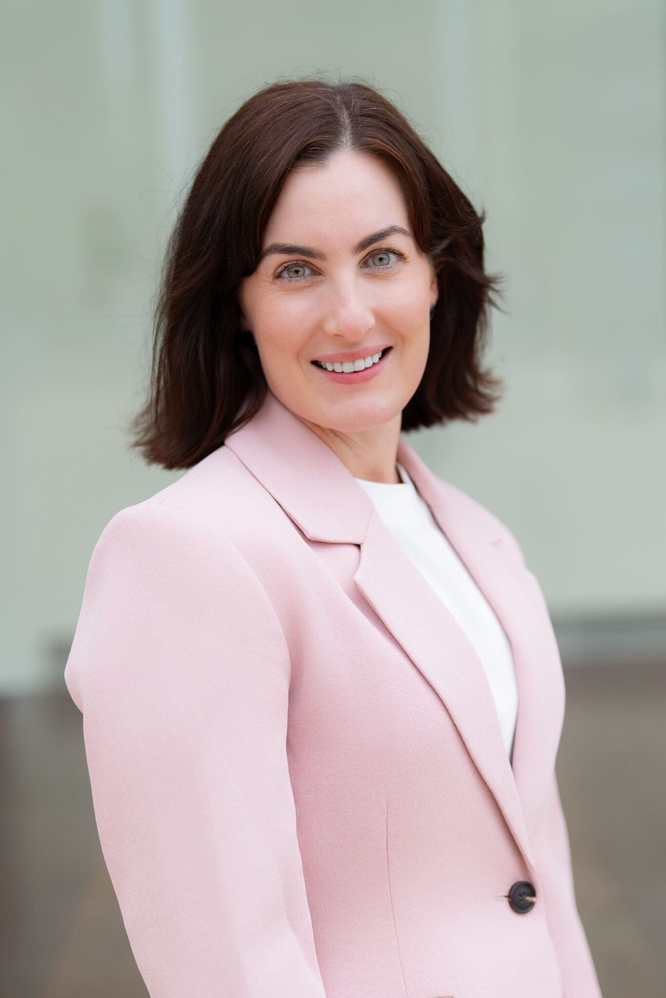 Young dark haired woman wearing a pink jacket having her headshot taken by professional Sydney photographer Georgie Greene