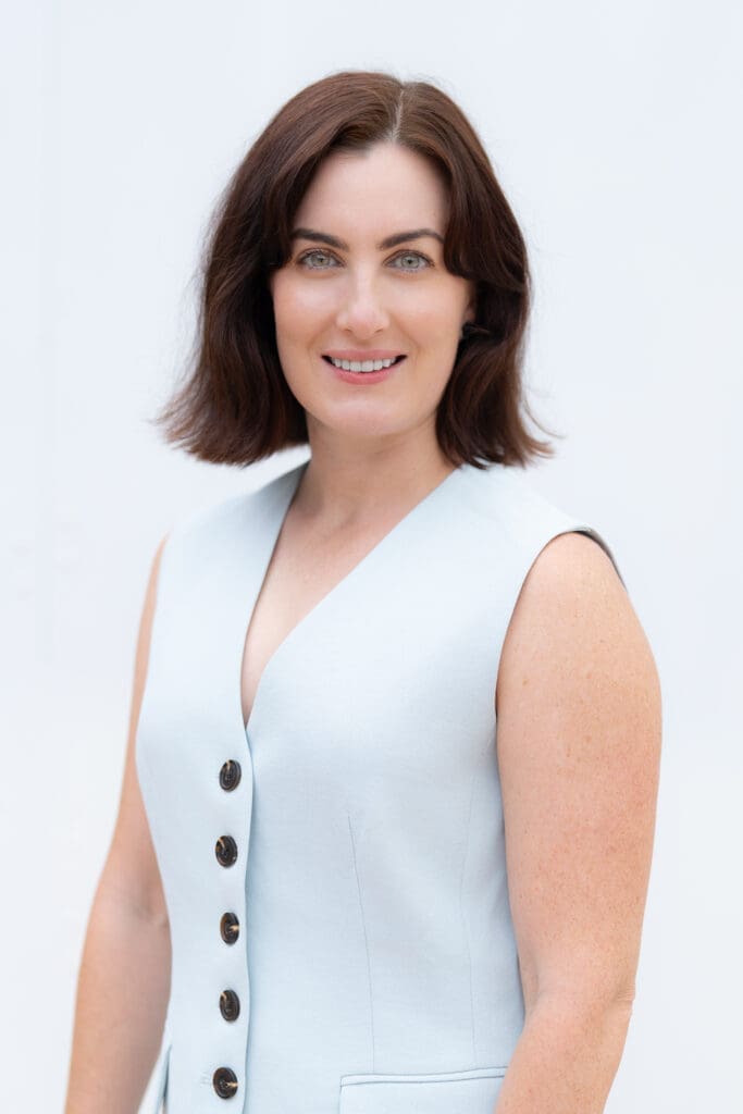 Young dark haired woman wearing a blue top having her portrait taken by Sydney headshot photographer Georgie Greene