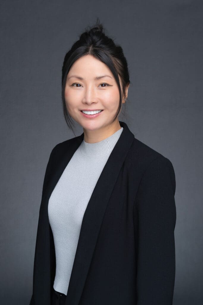 Young Asian woman with dark hair in a black jacket having her headshot taken by Sydney professional photographer Georgie Greene