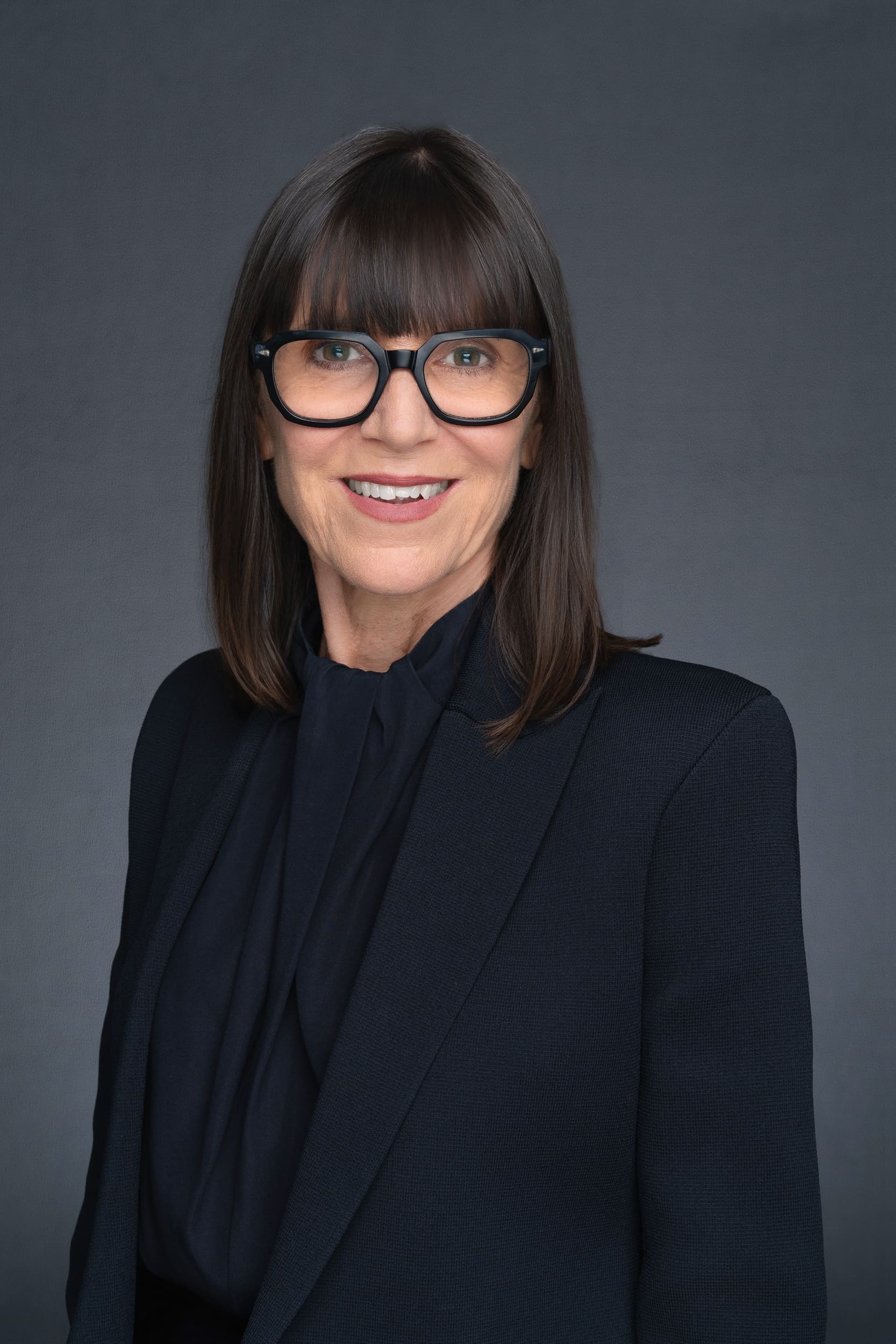 Older woman with dark hair in a black blouse wearing glasses having her headshot taken by Sydney headshot photographer Georgie Greene