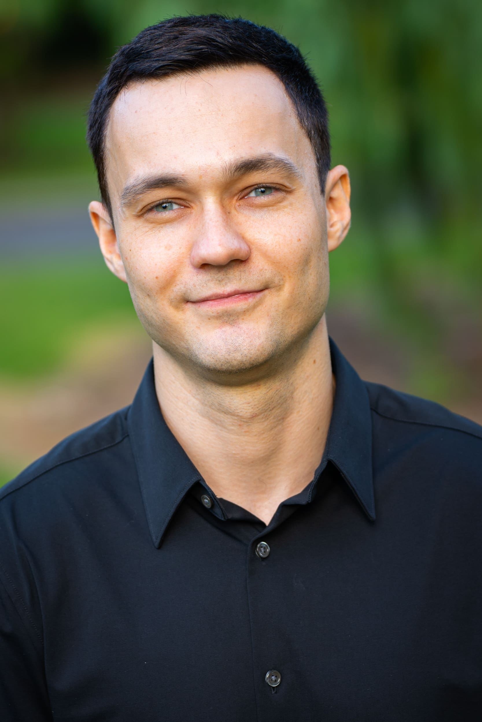 Young dark haired man wearing a dark shirt and smiling at the camera having his dating photo taken by Sydney dating photographer Georgie Greene