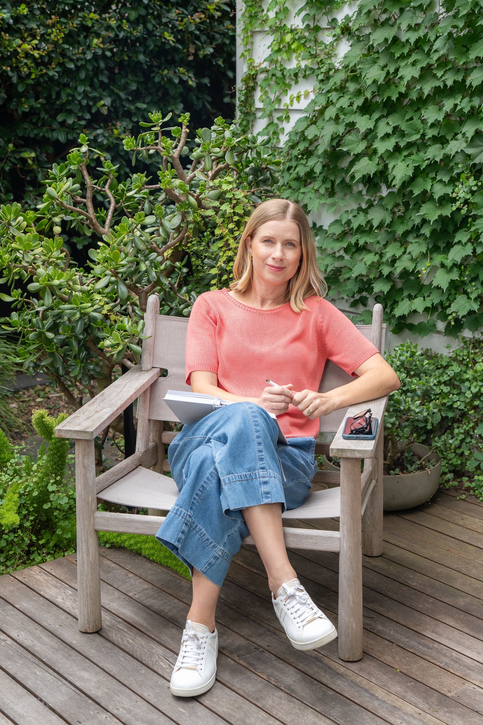 Woman in a coral top sitting in a chair and having her personal branding taken by Sydney personal branding photographer Georgie Greene