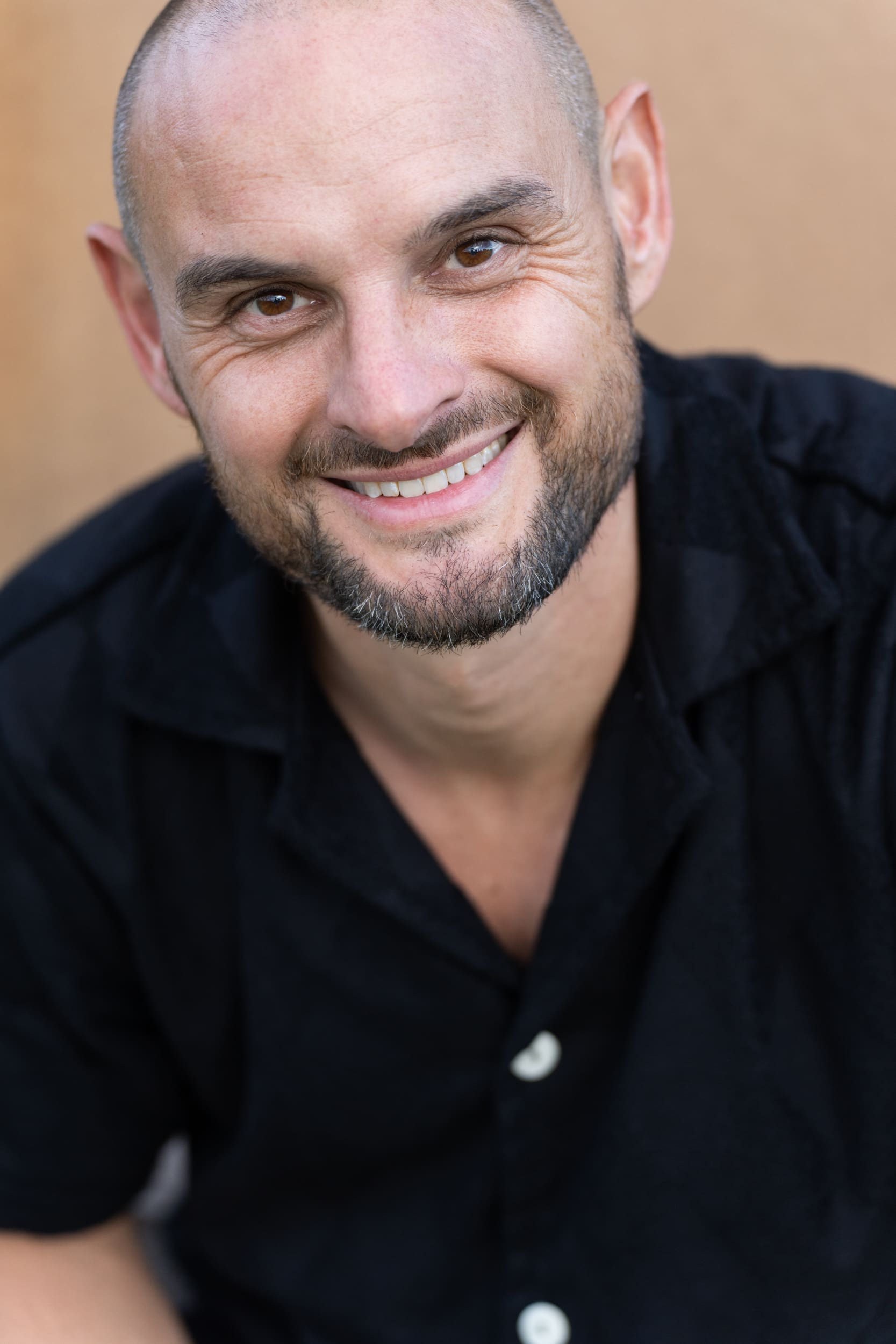 Young bald man wearing a black shirt and smiling at the camera having his dating photo taken by Sydney dating photographer Georgie Greene