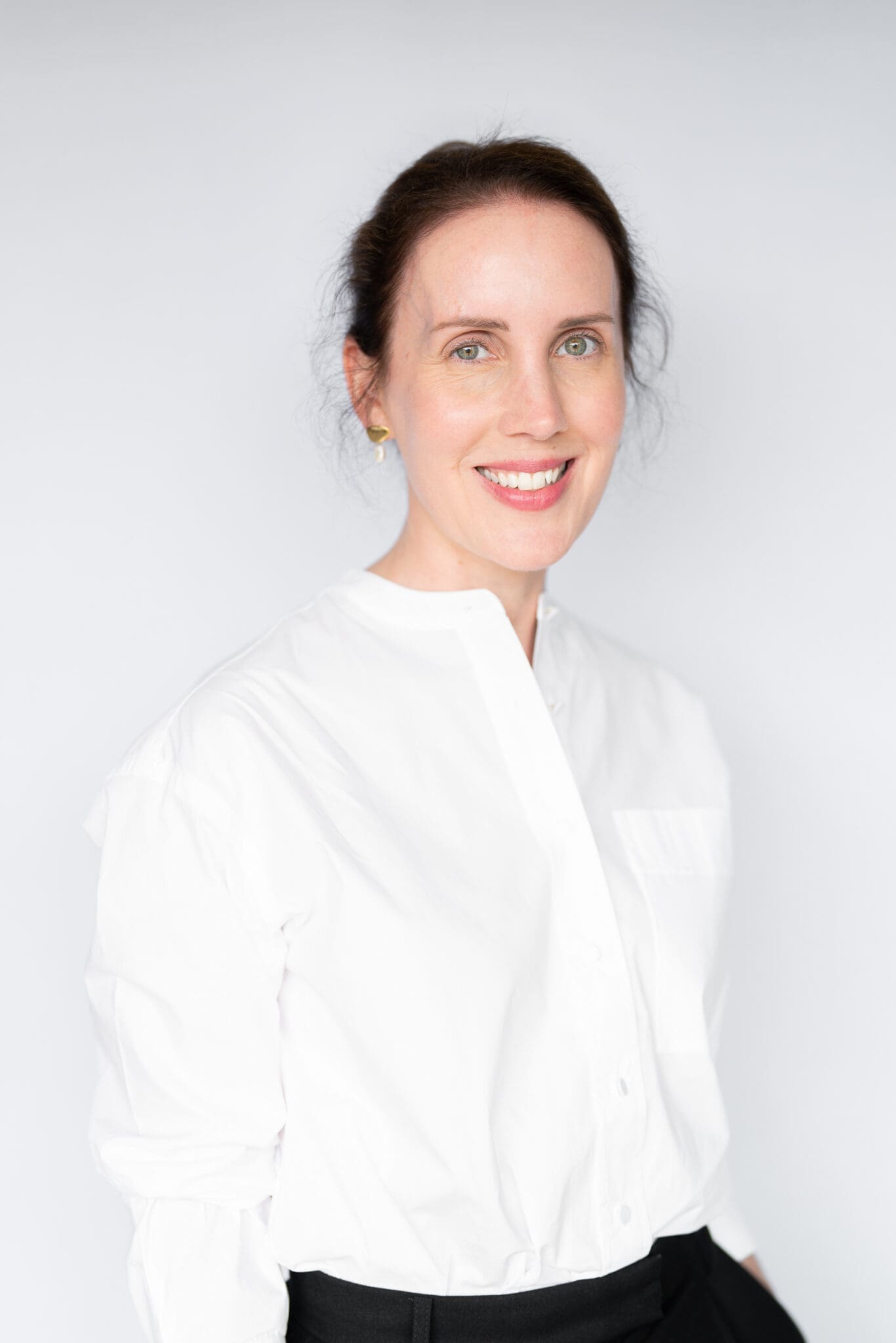 Young dark haired woman wearing white shirt and having her natural light headshot taken by top Sydney headshot photographer Georgie Greene